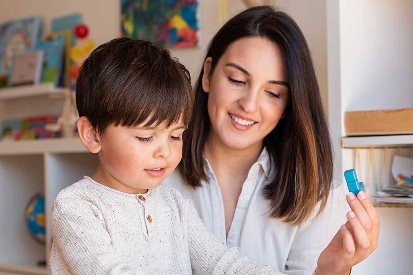 A mother and son playing with a wooden puzzle at home