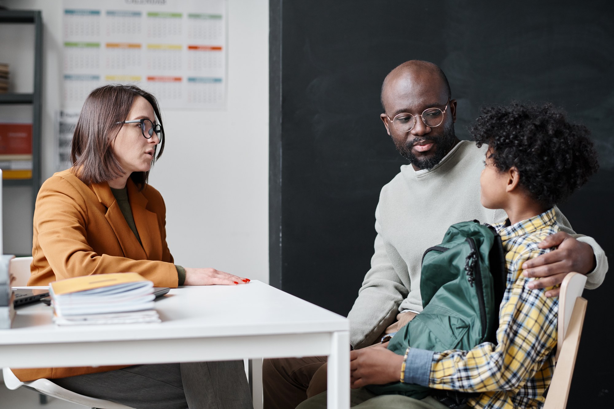 A teacher and parent talking with a child about school coordination